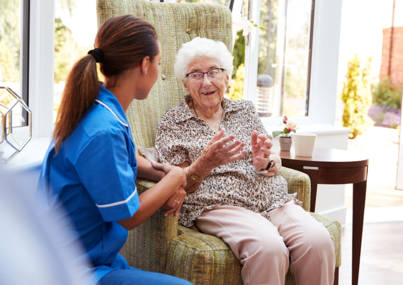 Senior engaging in conversation with nurse.