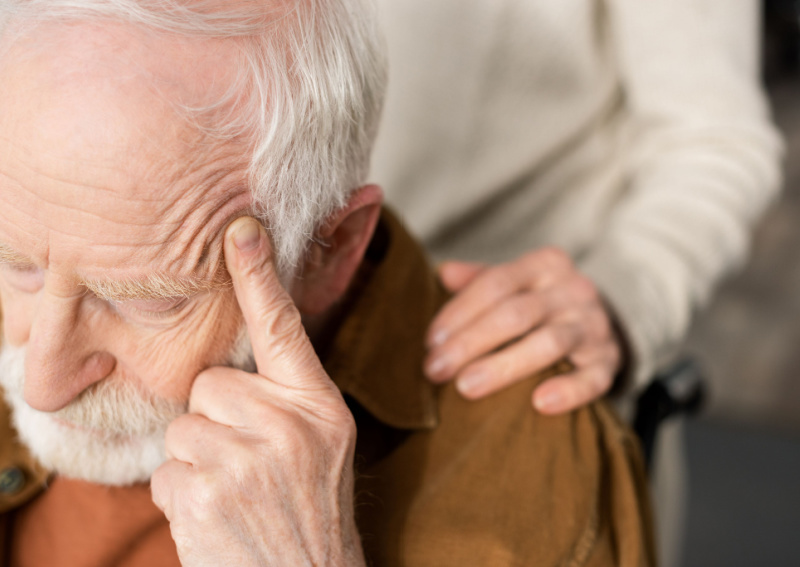 Elderly man on a wheelchair with his finger on his temple