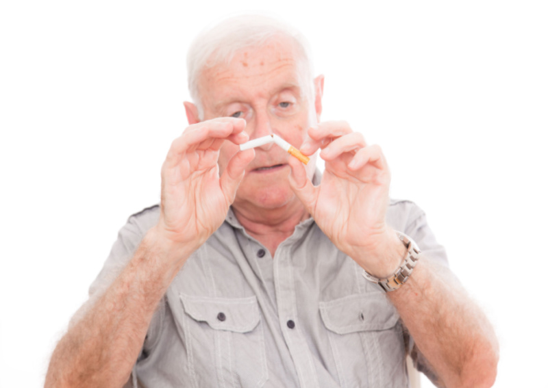 Senior man breaking cigarette in half