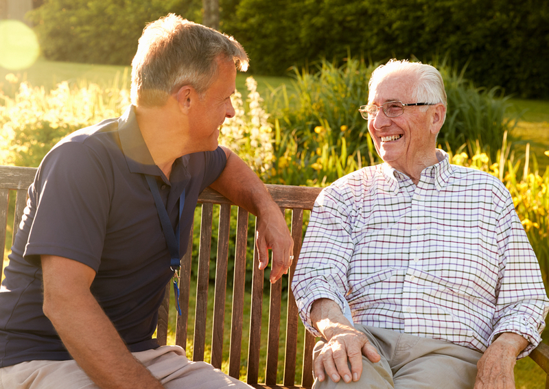 A man visiting a happy relative in senior living.