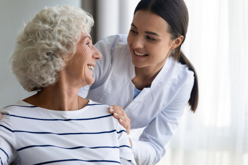 A woman helping a senior at a skilled nursing home.