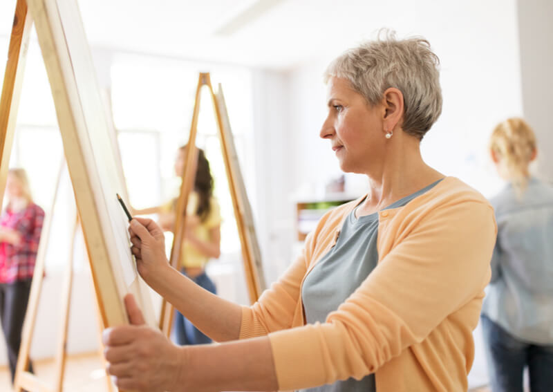 A senior woman painting.