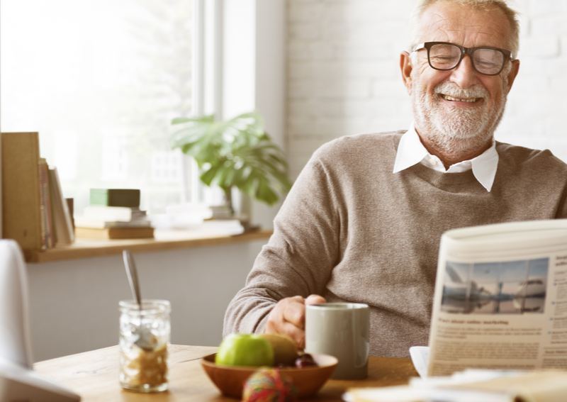 Man happily reading a newspaper and holding cup