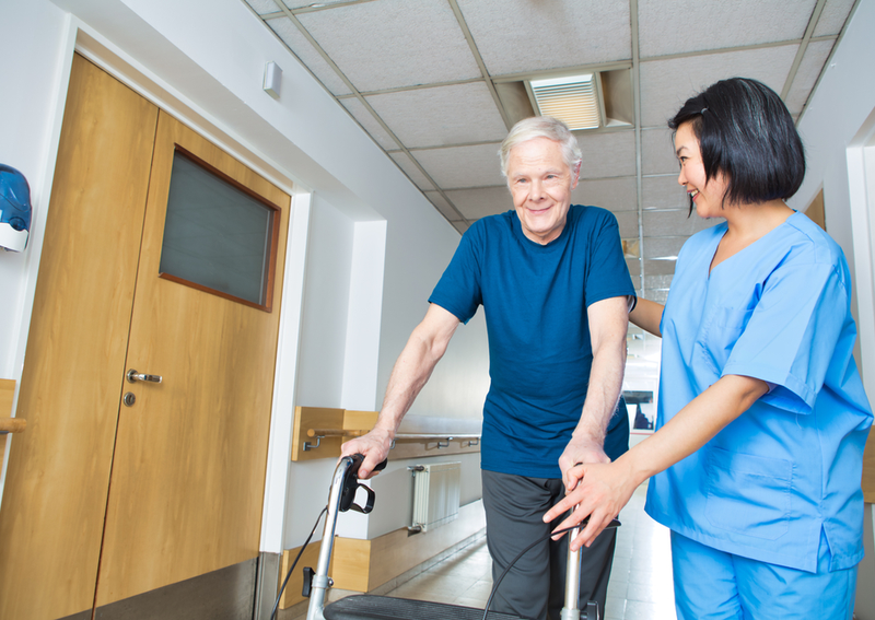 A nurse helps a man with a walker.