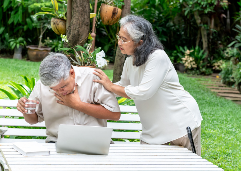 Elderly patient is choking and being assisted by another individual.