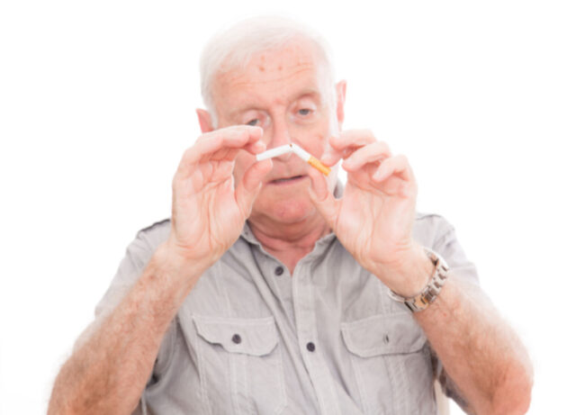 Senior man breaking cigarette in half