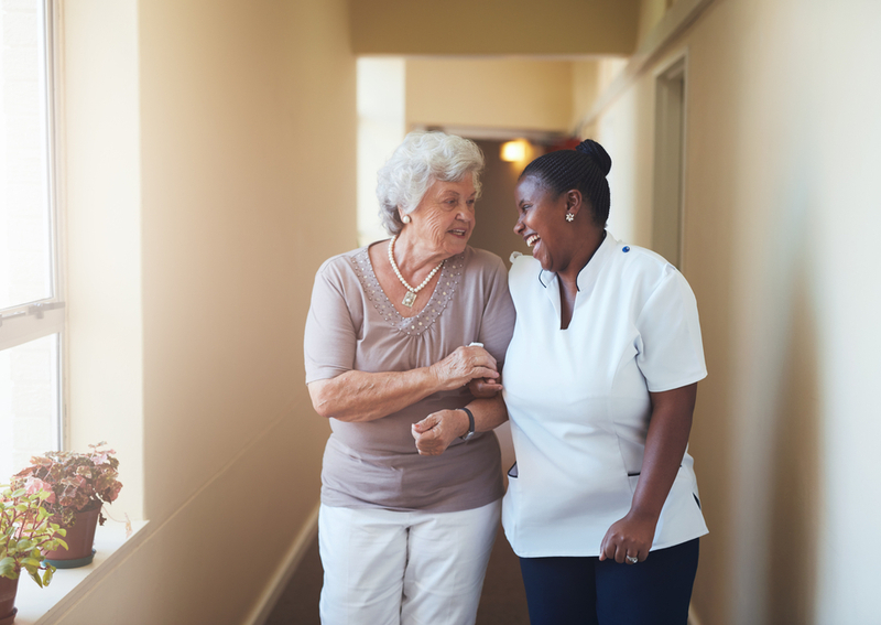 A woman in an assisted living home with a caretaker.