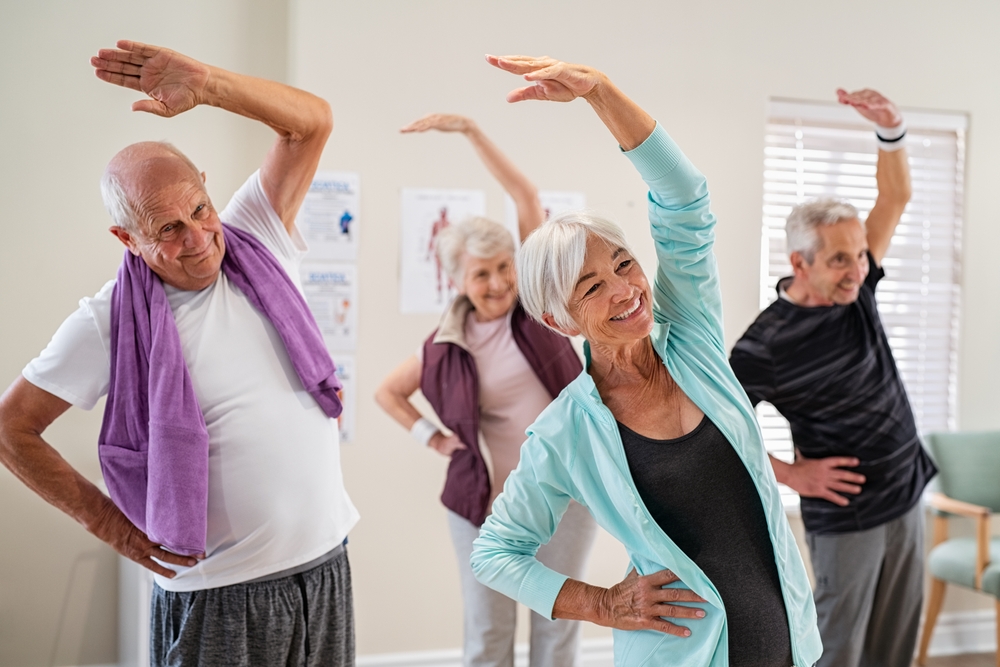 Group Of Seniors Doing Stretching Exercise Together At Retirement Center