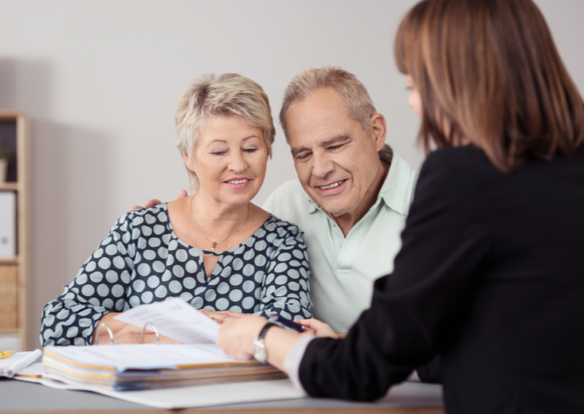 Two elderly people sitting talking to woman with back facing the camera