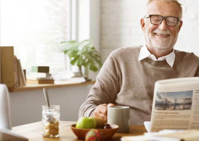 Some-Independent-Senior-Living-Amenities-That-You-Will-Not-Get-At-Home Man happily reading a newspaper and holding cup