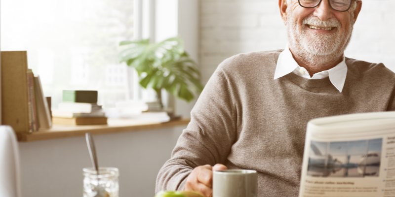 Some-Independent-Senior-Living-Amenities-That-You-Will-Not-Get-At-Home Man happily reading a newspaper and holding cup