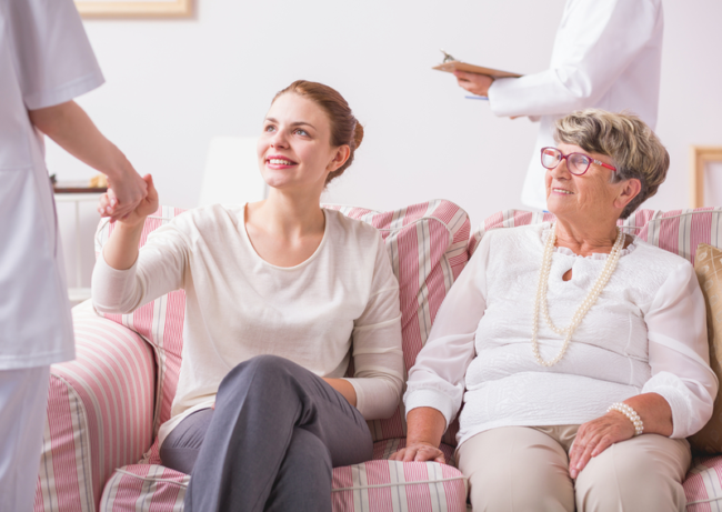 caretaker and patient sitting on couch and being assisted by specialist