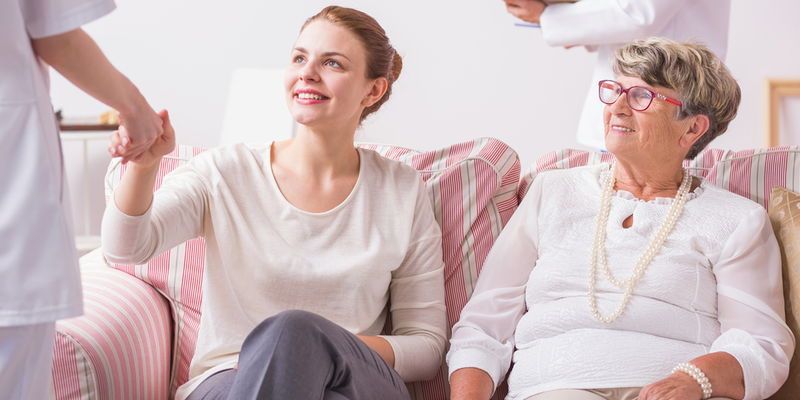 caretaker and patient sitting on couch and being assisted by specialist