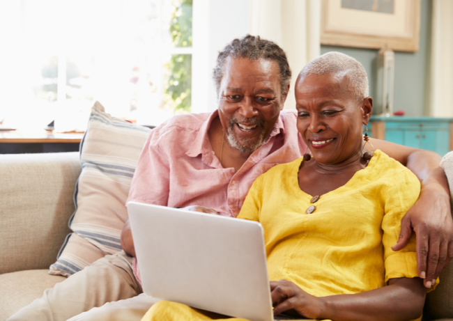What Is The Role Of Technology In Memory Care?  Senior couple smiles at computer screen