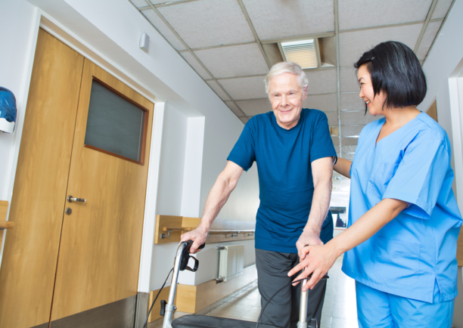 virtual-visit-assisted-living A nurse helps a man with a walker.